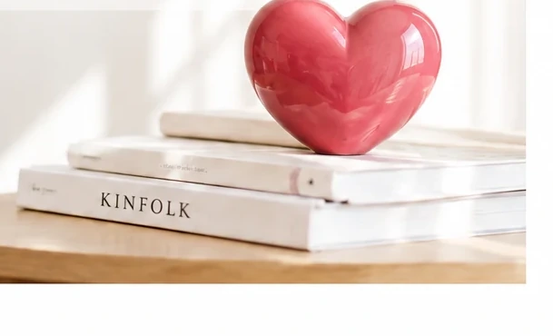 A ceramic heart resting on a stack of books in soft daylight